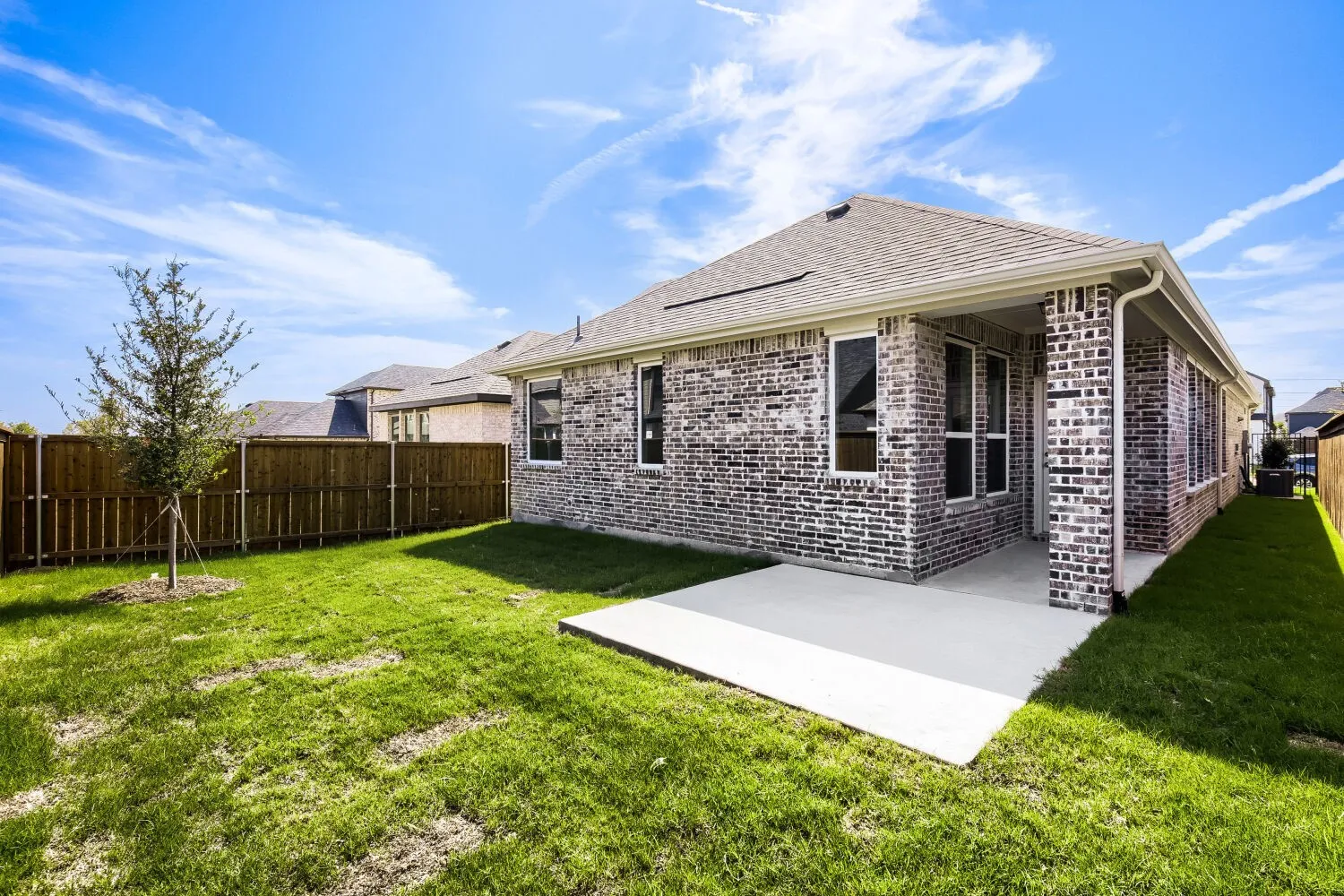 Brick exterior, covered patio, concrete patio, privacy fencing, and a grassy lawn