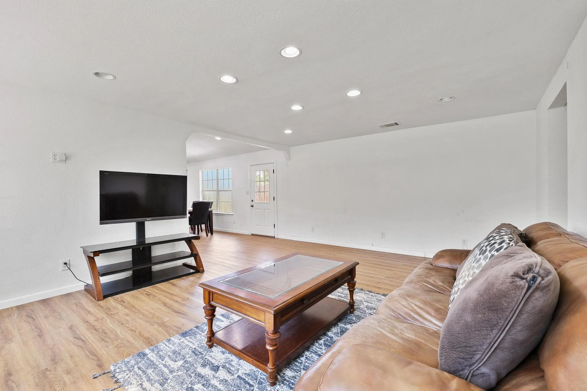 Open-concept living space with recessed lighting, wood-finish flooring, and white wall finishes