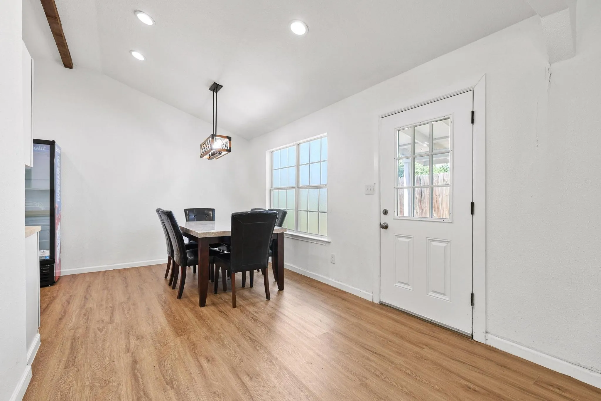 Dining space featuring wood-finish flooring, a vaulted ceiling with recessed lighting, and a modern rectangular chandelier