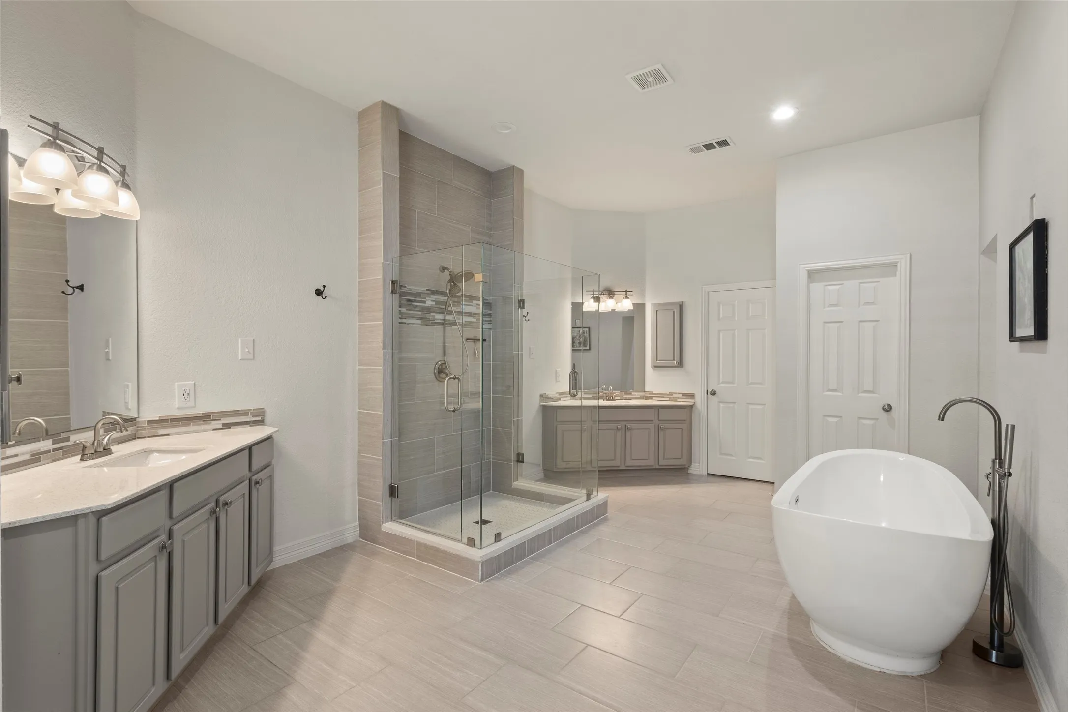 New frameless shower surround, soaking tub, separate vanities with quartz countertops