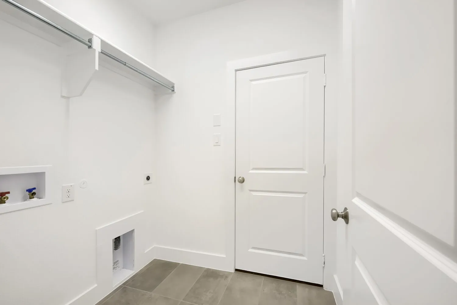 Utility space with tile flooring, a built-in shelf, and a clothing rod