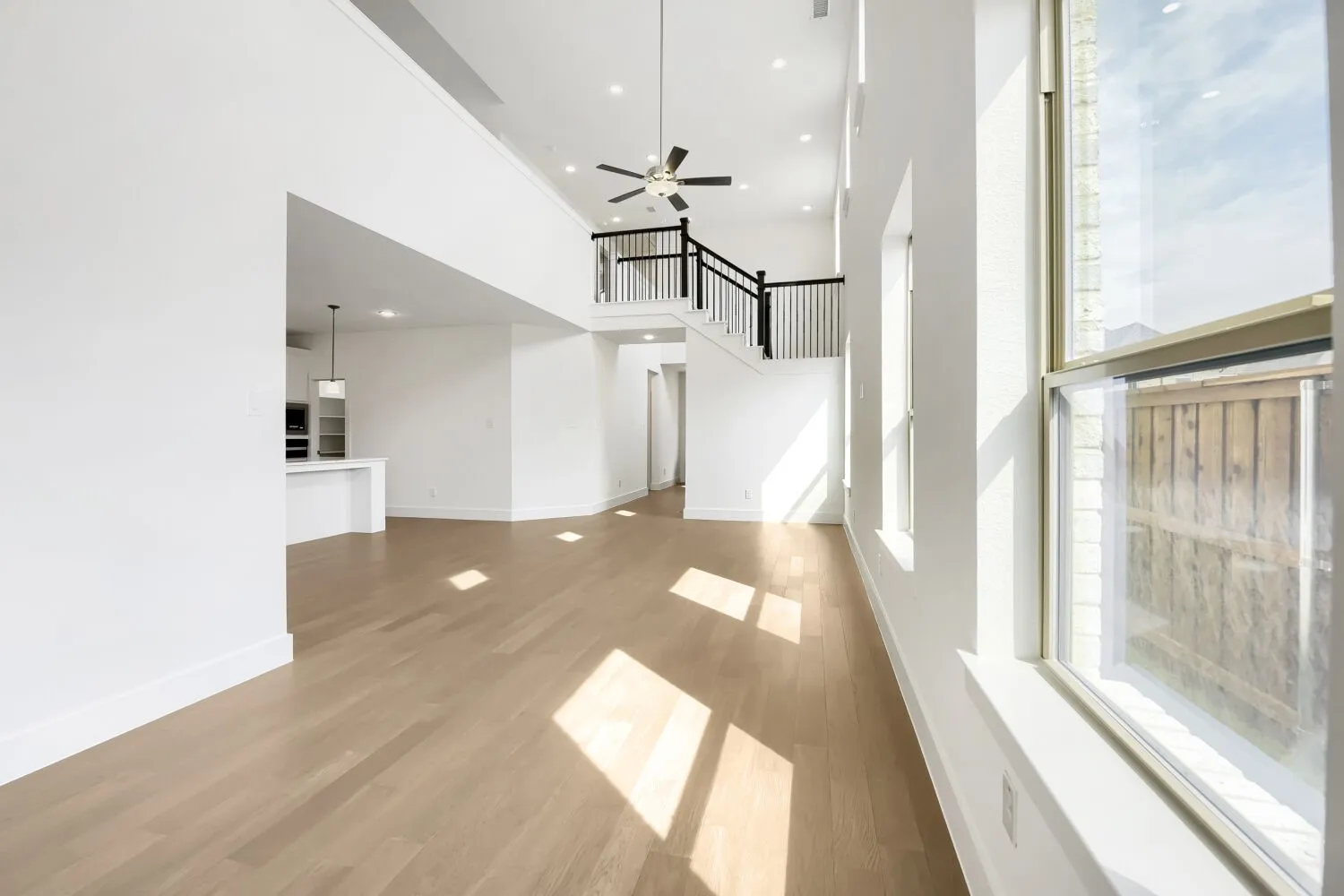 Two-story living area with high ceilings, wood-finish flooring, and multiple windows