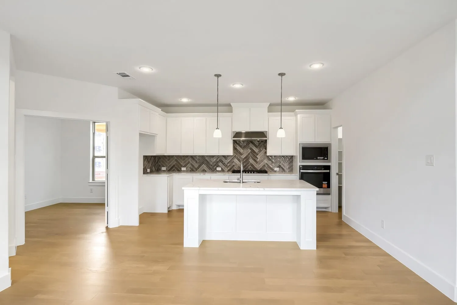 Kitchen with a central island, recessed lighting, white cabinetry, integrated stainless steel appliances, and wood-finish flooring