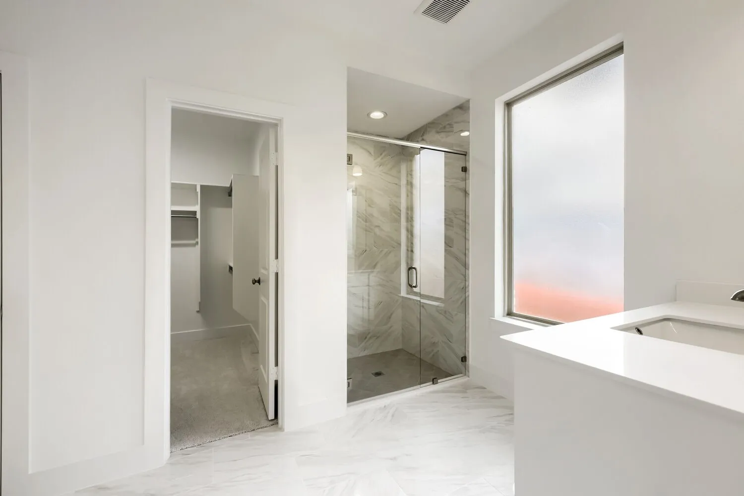 Walk-in shower with clear glass enclosure and tiled walls
