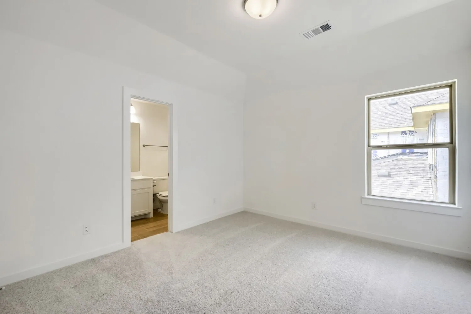 Recessed lighting, carpet flooring, and a single window with white trim