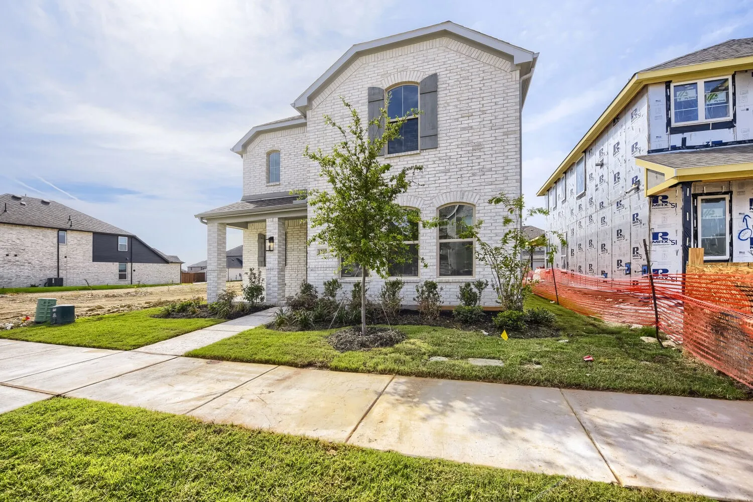 Two-story brick exterior with arched windows, a covered front porch, and mature landscaping