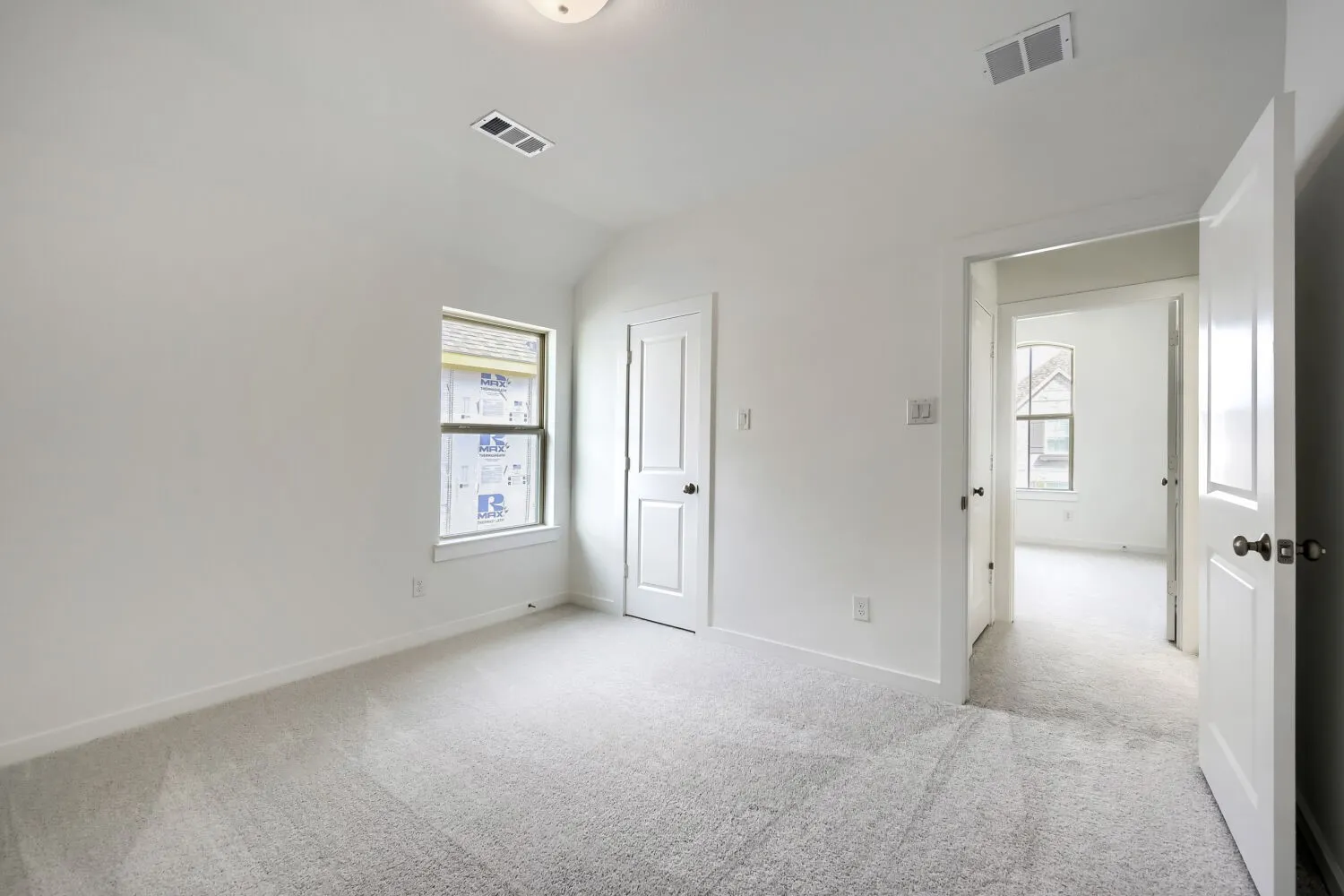 Carpeted room featuring a single window, white walls, and a ceiling light fixture