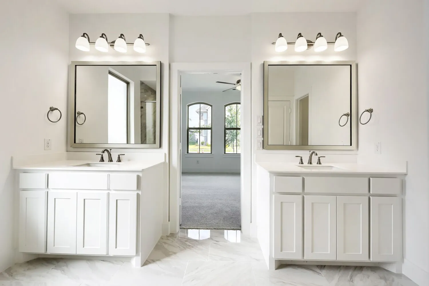 Dual vanities with white cabinetry and integrated sinks, brushed nickel fixtures, and individual wall-mounted mirrors