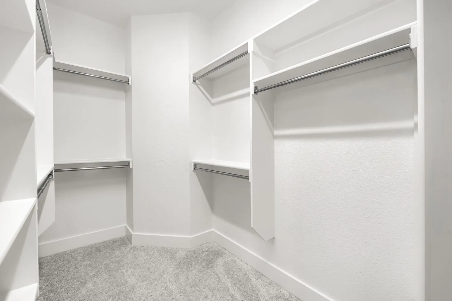 Walk-in closet with integrated white shelving, multiple hanging rods, and carpet flooring