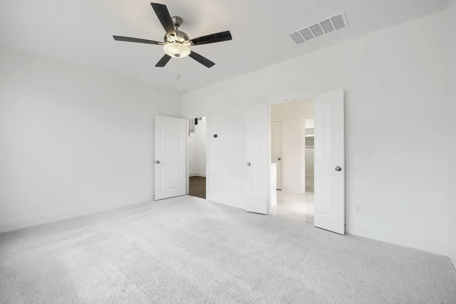 Plush carpeting, bright white walls, and a ceiling fan with integrated lighting