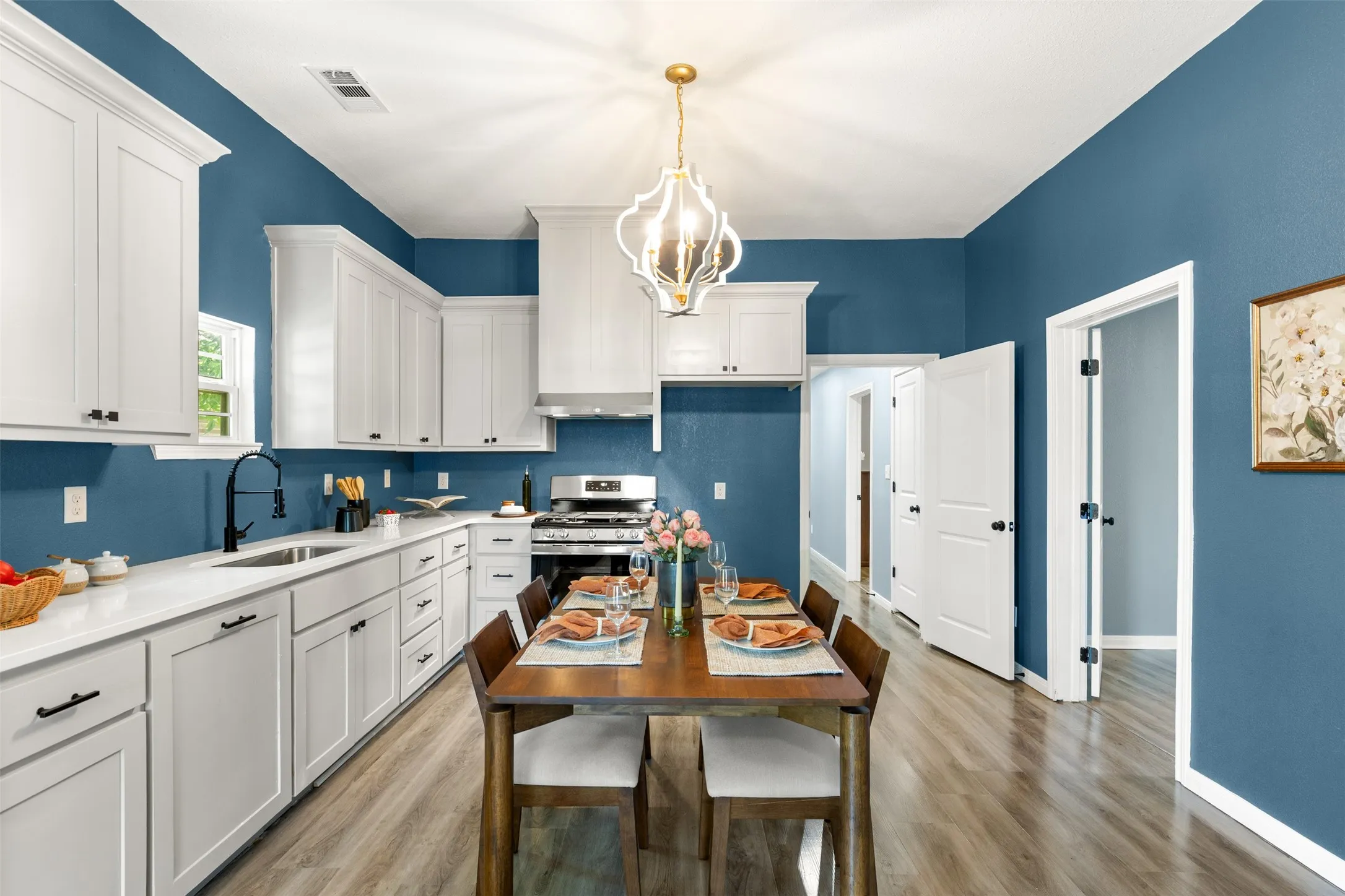 Kitchen and dining area featuring white shaker cabinetry, light-colored countertops, and wood-finish flooring