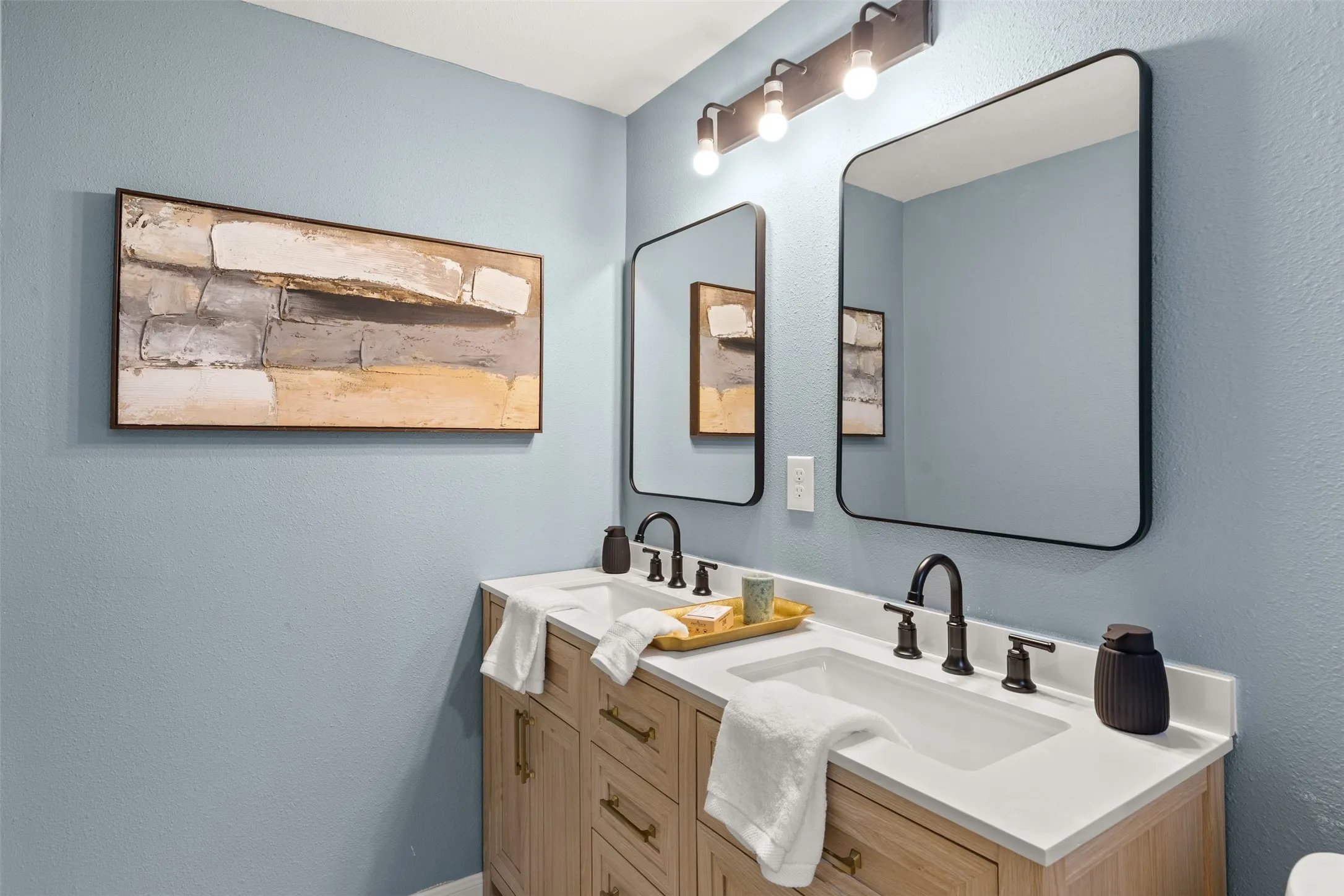 Dual rectangular undermount sinks with matte black fixtures set into a light-toned countertop