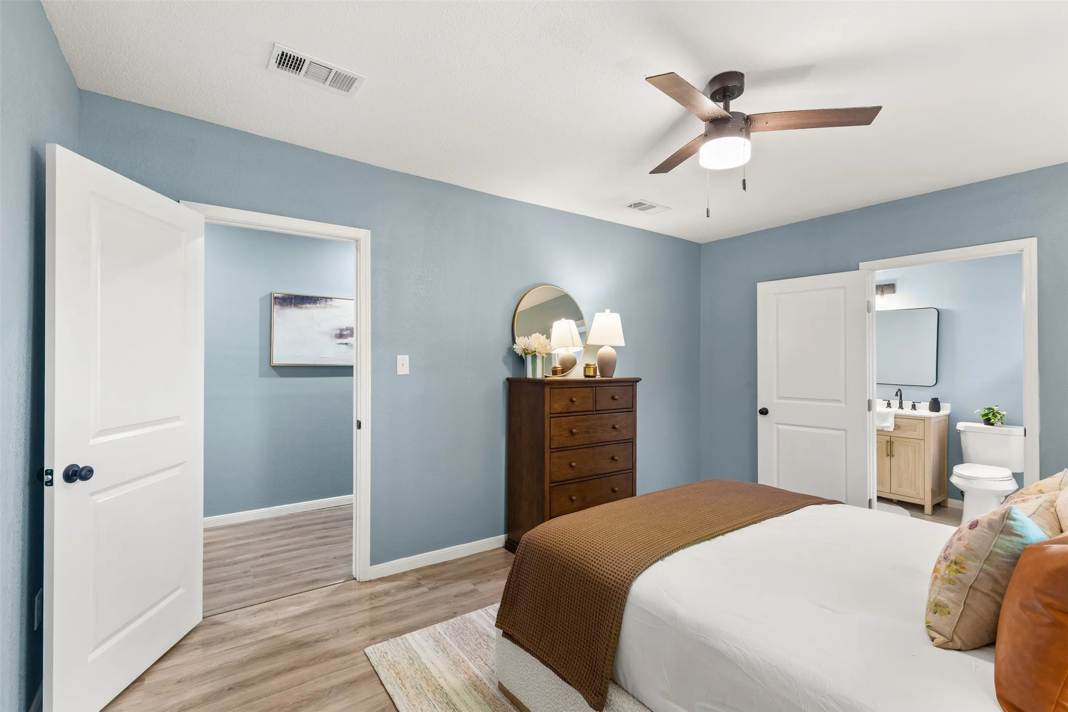 Bedroom featuring wood-finish flooring, light blue walls, and a ceiling fan with integrated lighting