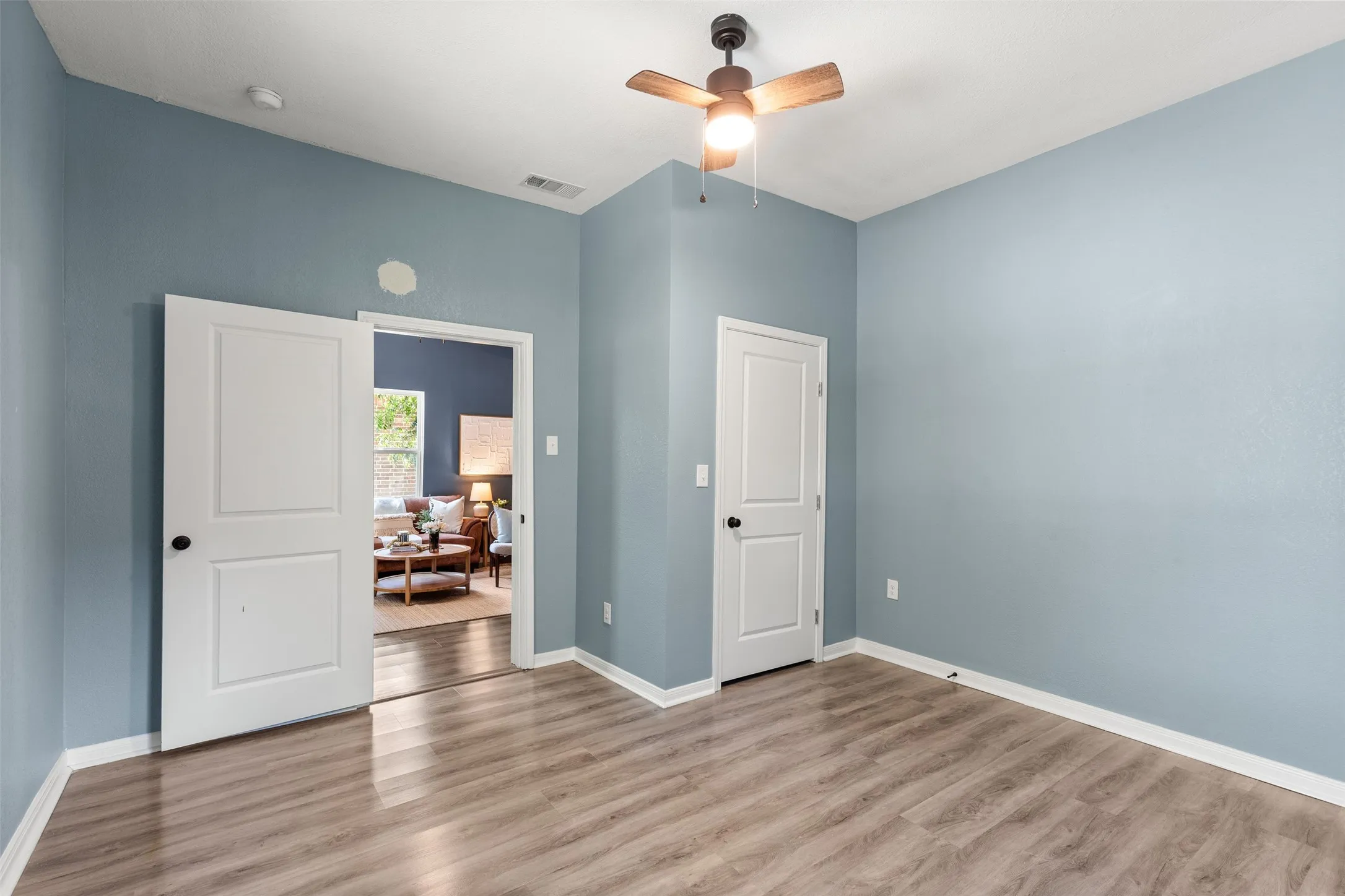 Interior room featuring wood-finish flooring, light blue wall paint, and white trim