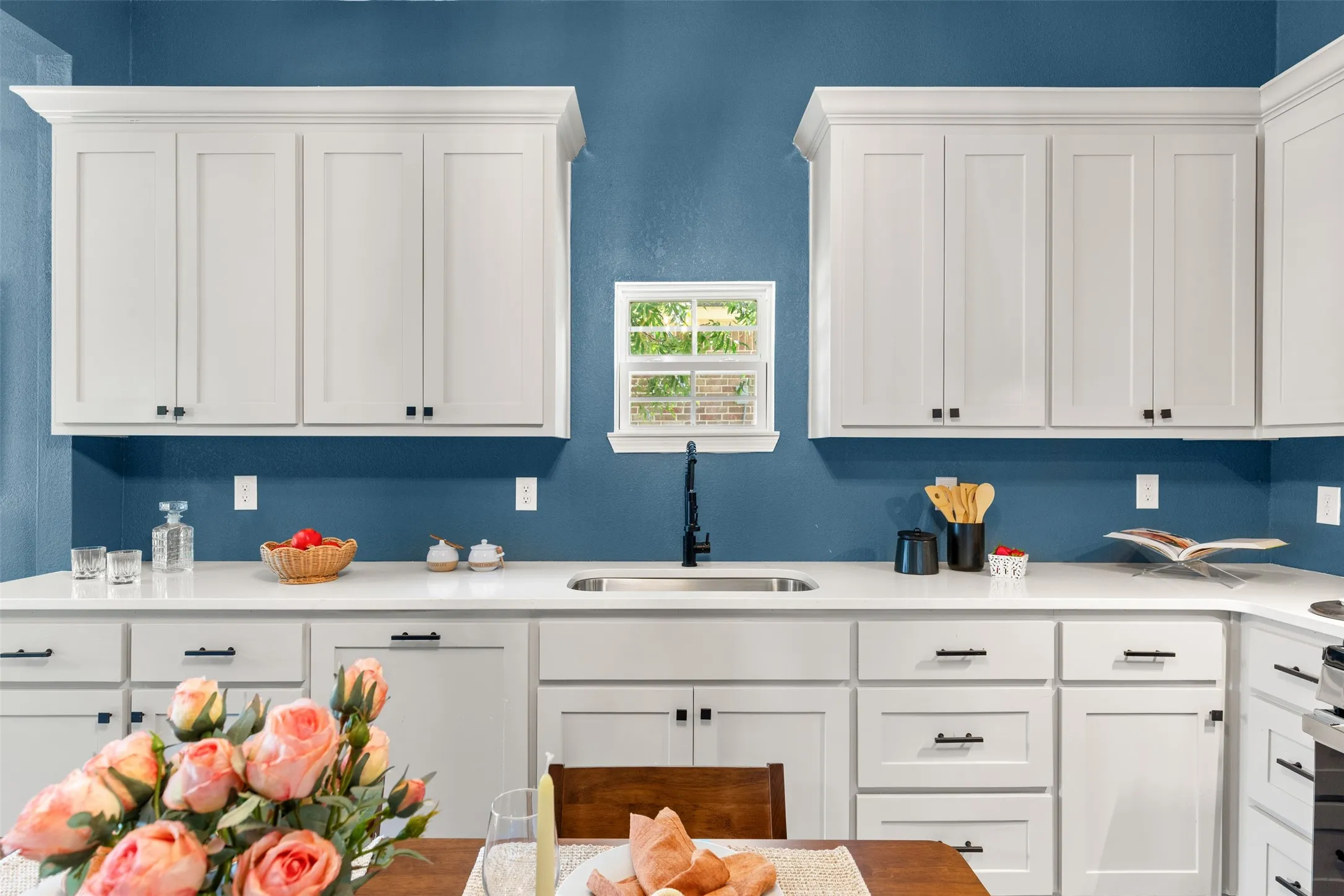 Kitchen featuring white shaker-style cabinetry, white countertops, and a stainless steel sink with a matte black gooseneck faucet