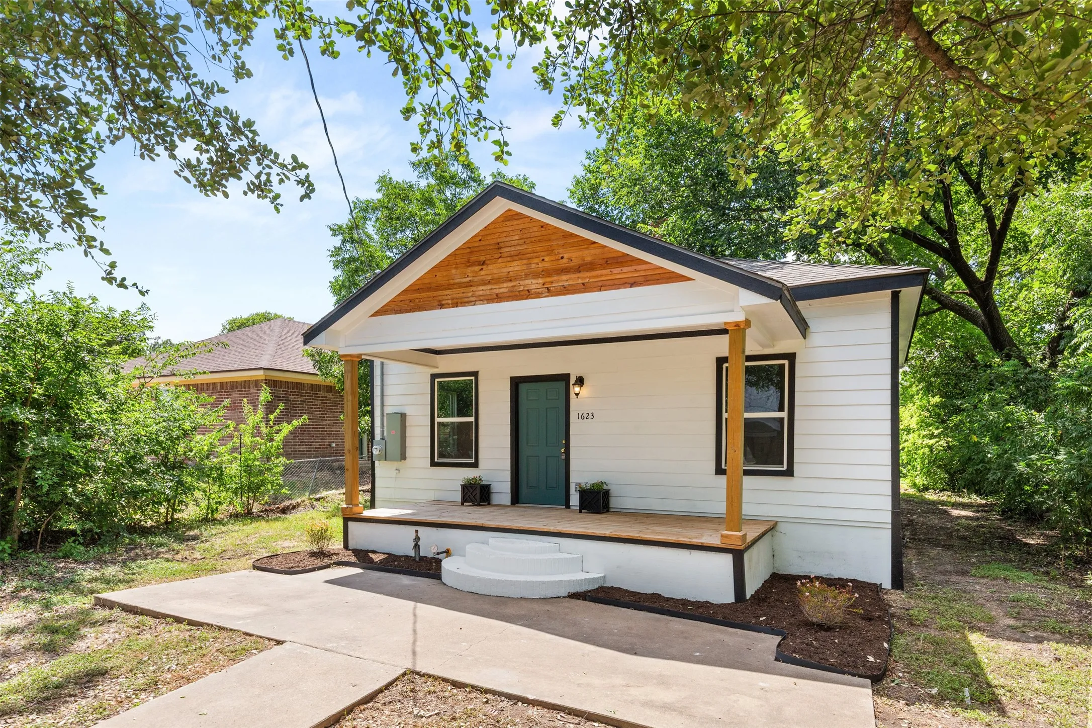White horizontal siding exterior with a wood-clad front gable and black trim accents