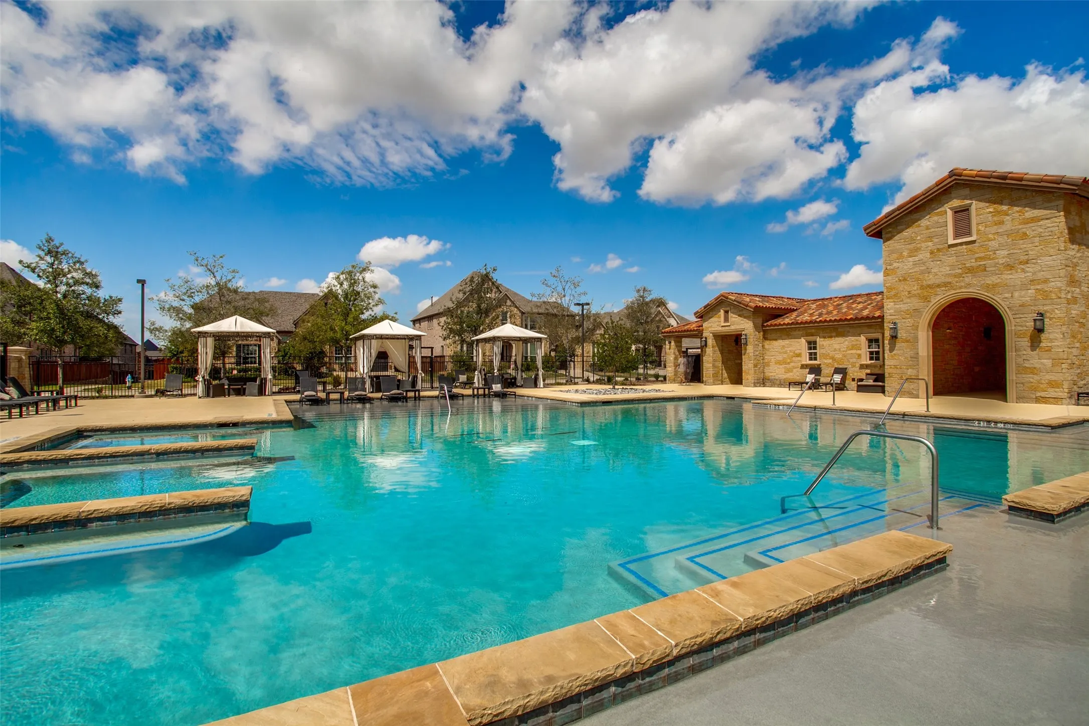 Resort-style community swimming pool featuring a tanning ledge and integrated spa