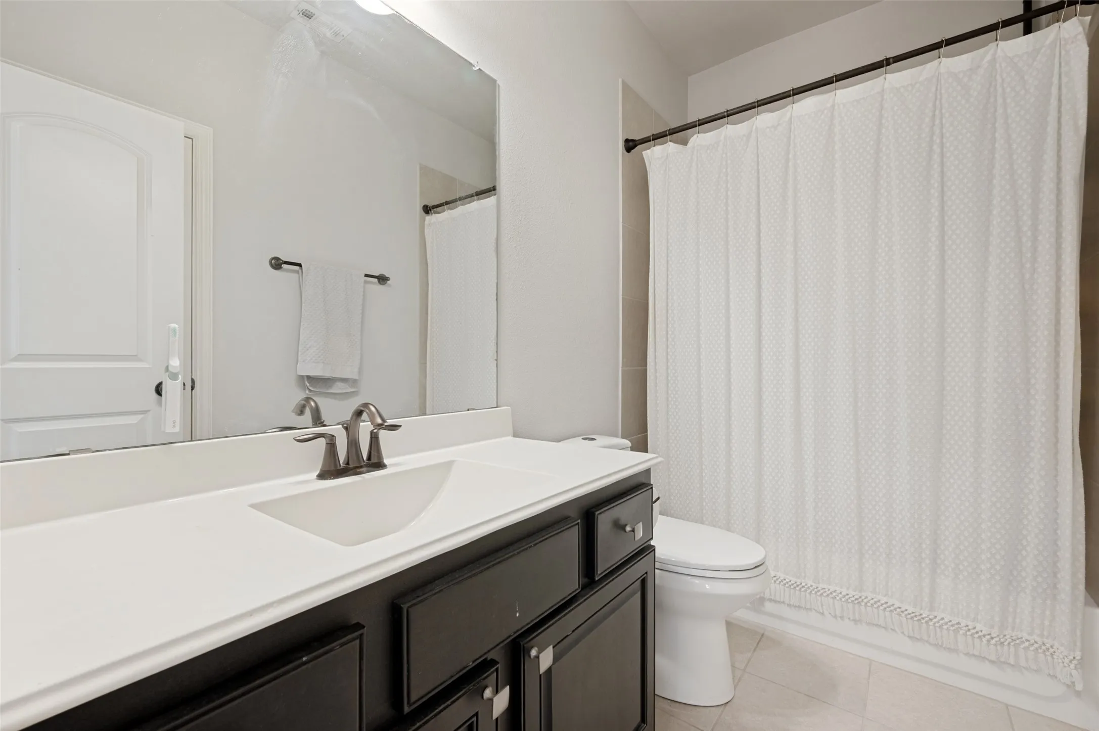 Bathroom featuring a dark wood-finish vanity with a white countertop, an undermount sink, and a bronze-tone faucet