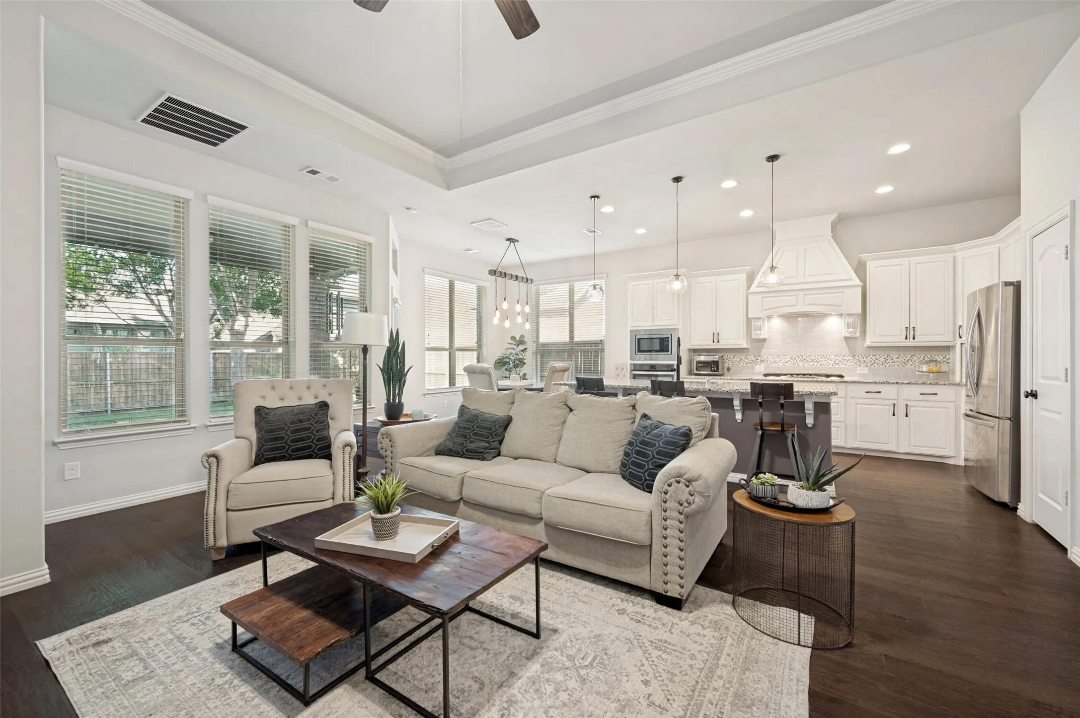 Open-concept living space featuring wood-finish flooring, a tray ceiling, and recessed lighting