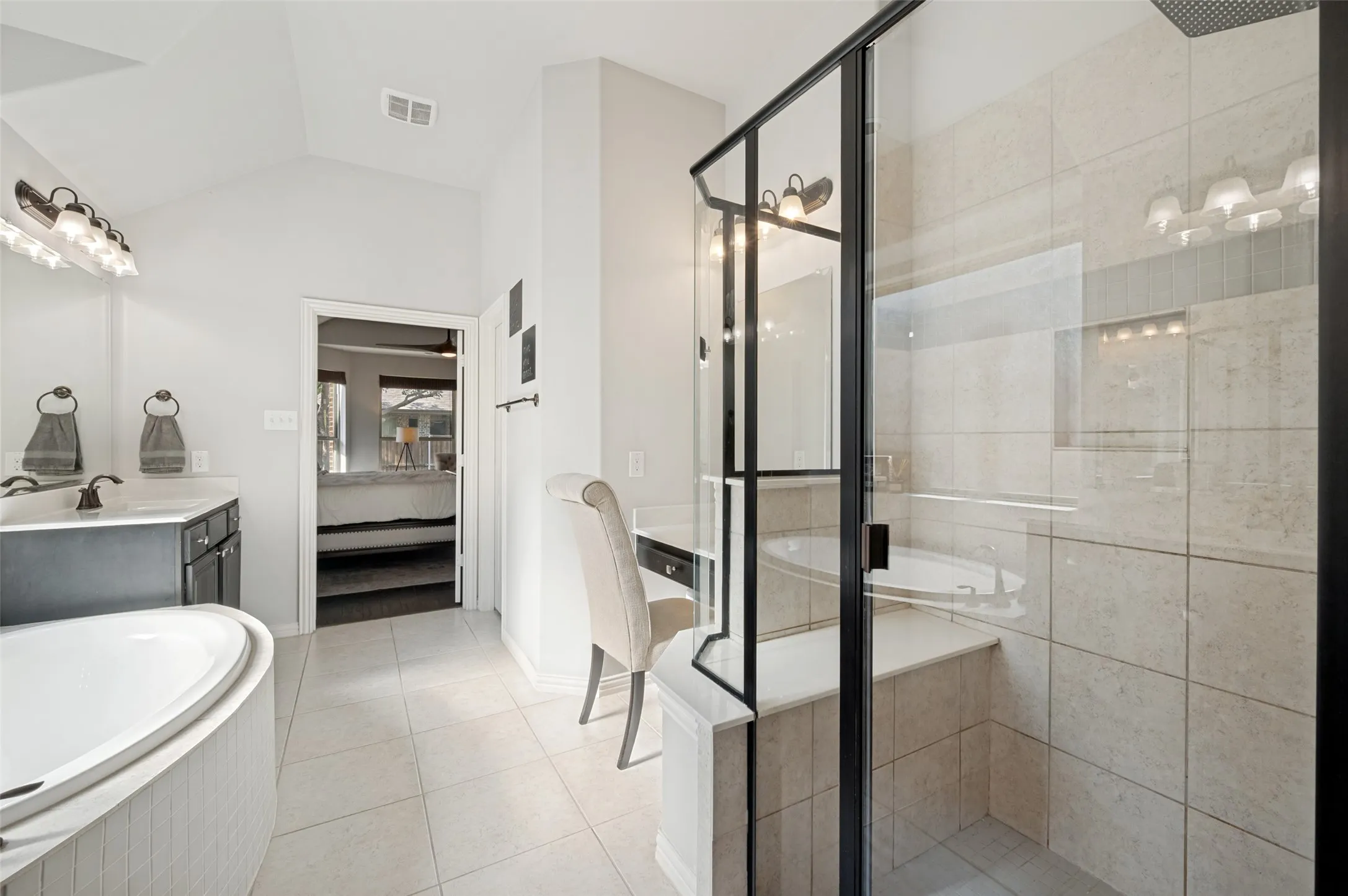 Bathroom featuring a corner soaking tub, a tiled shower with a black-framed glass enclosure, and a built-in vanity desk
