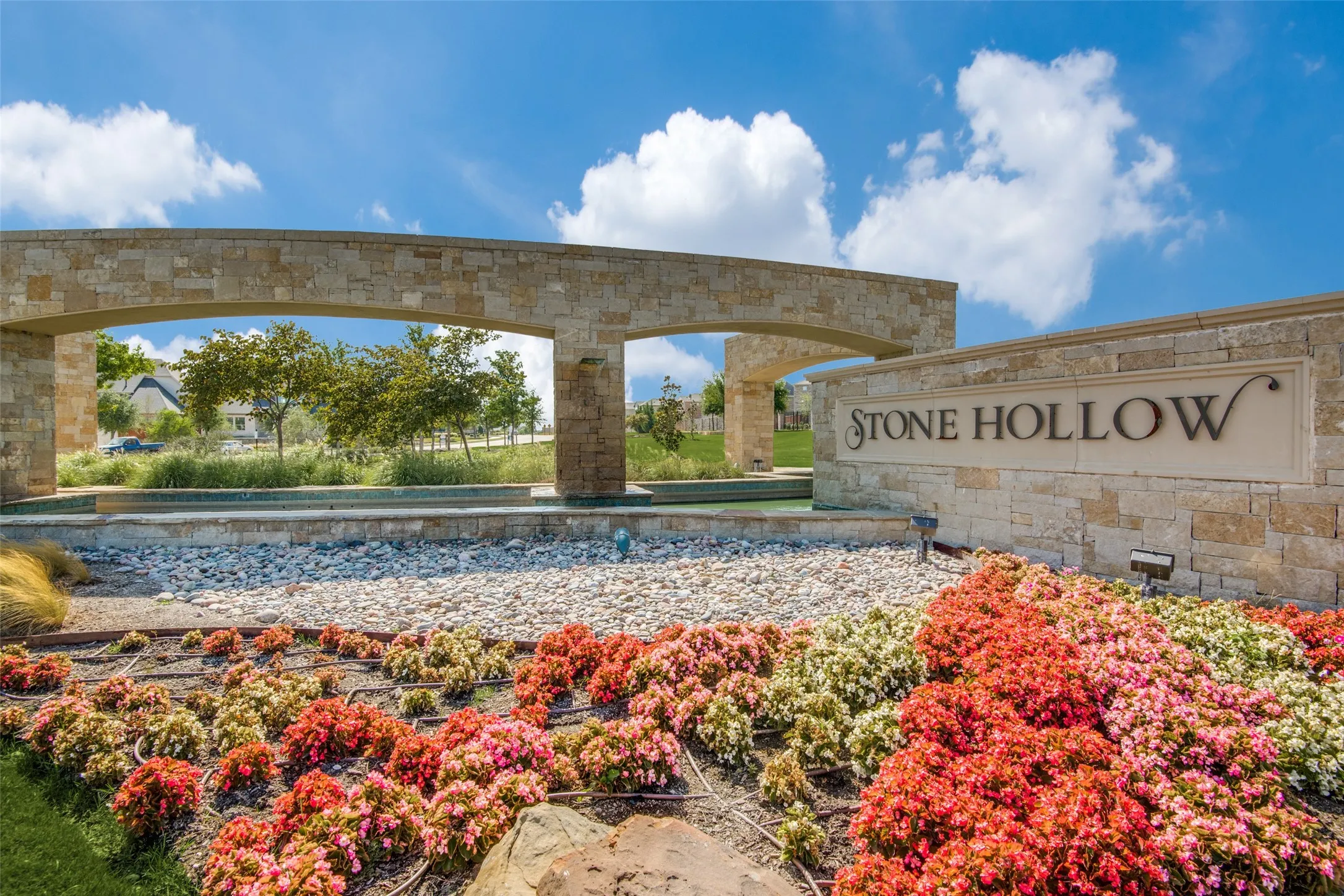 Stone Hollow community entrance featuring a stone archway and matching signage