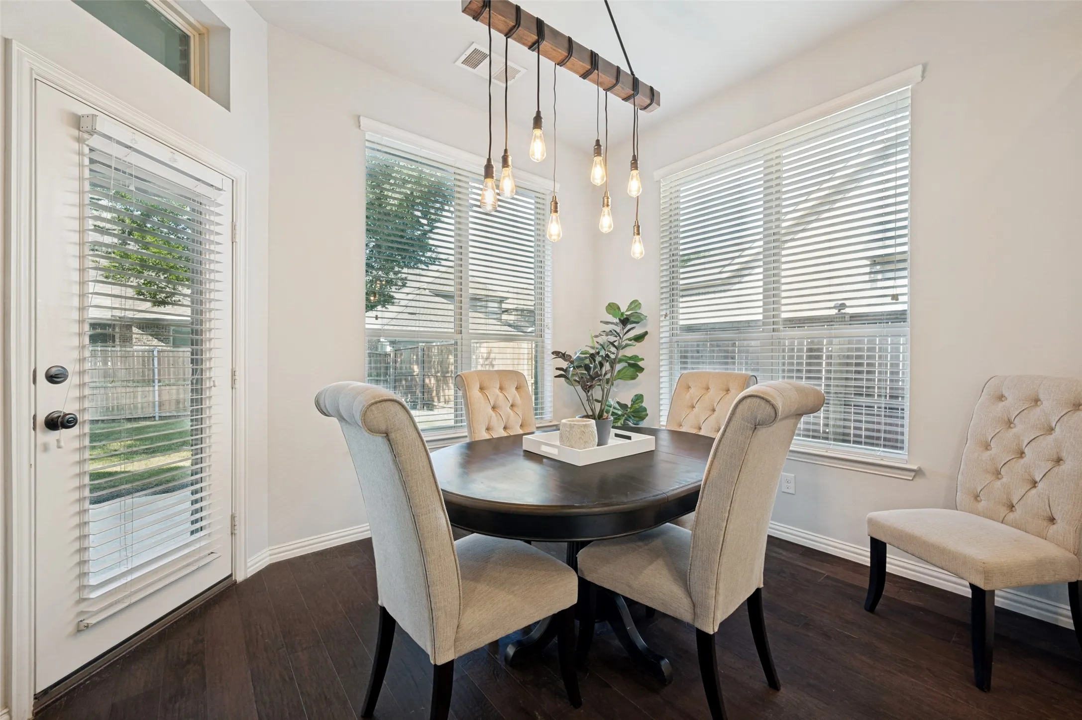 Dining area featuring wood-finish flooring, two large windows with blinds, and a door with an upper transom window