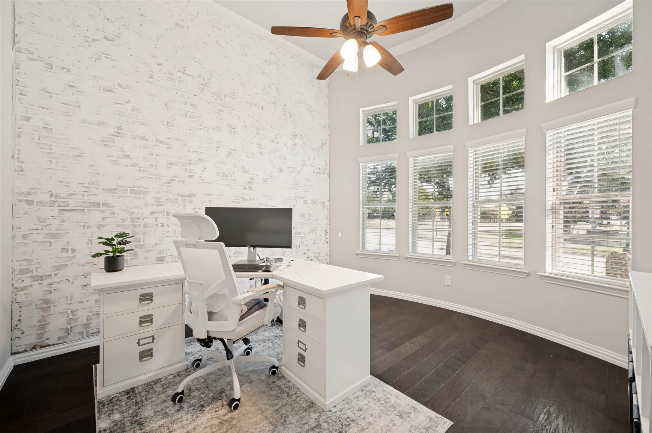 Vaulted ceiling featuring a wood-finish ceiling fan and a whitewashed brick accent wall