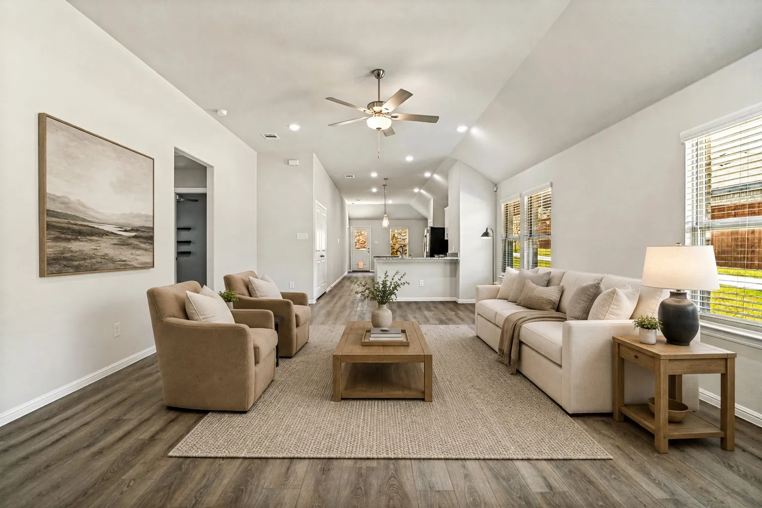 Spacious open-concept living area featuring wood-finish flooring, neutral wall finishes, and abundant natural light from multiple windows (virtually staged)