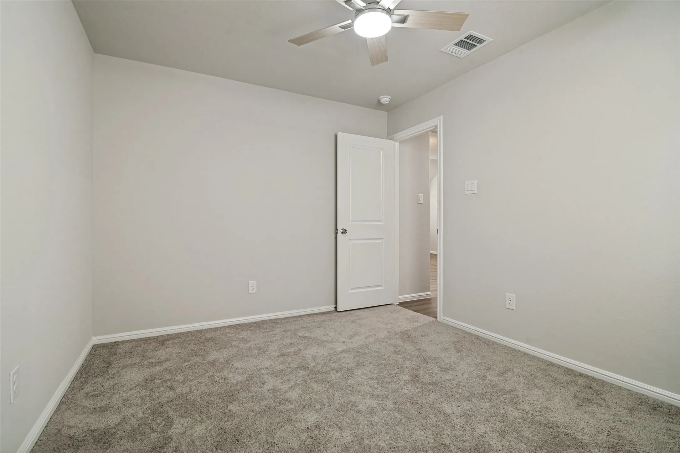 Neutral wall color with white trim, complementing the grey carpet