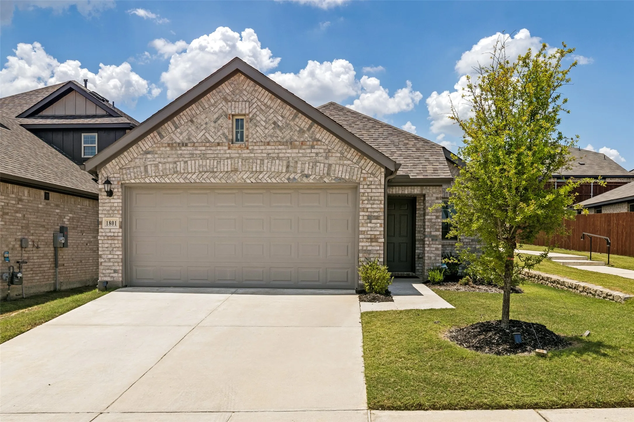 Brick and stone facade featuring an attached two-car garage, a covered entry, and a gabled roofline