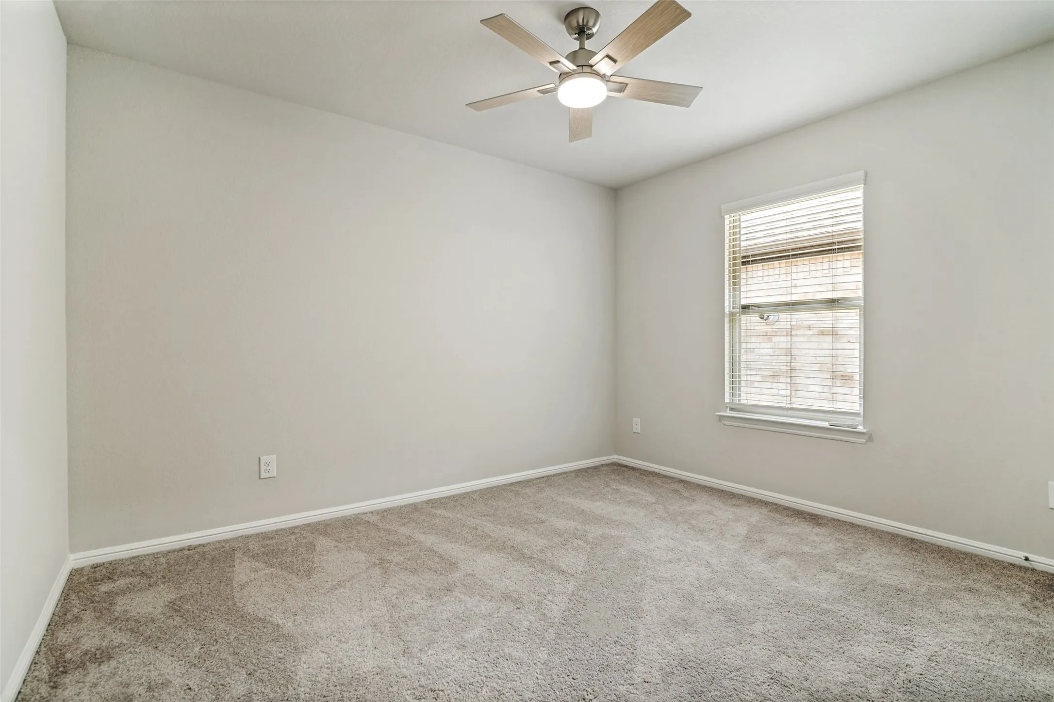 Freshly carpeted room with a ceiling fan light fixture, light gray walls, and white trim