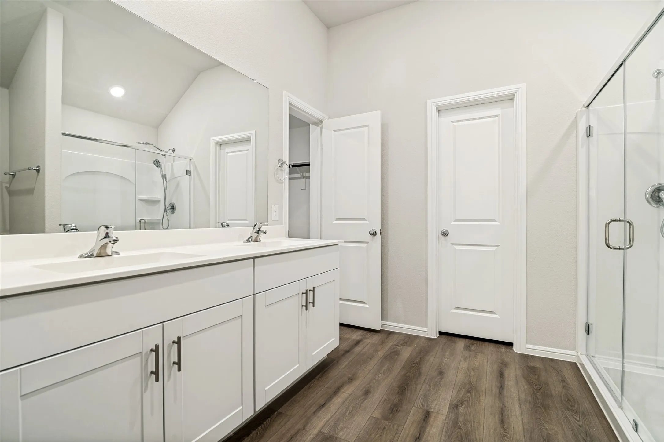 Bathroom featuring a dual vanity with white cabinetry, integrated sinks, and chrome faucets