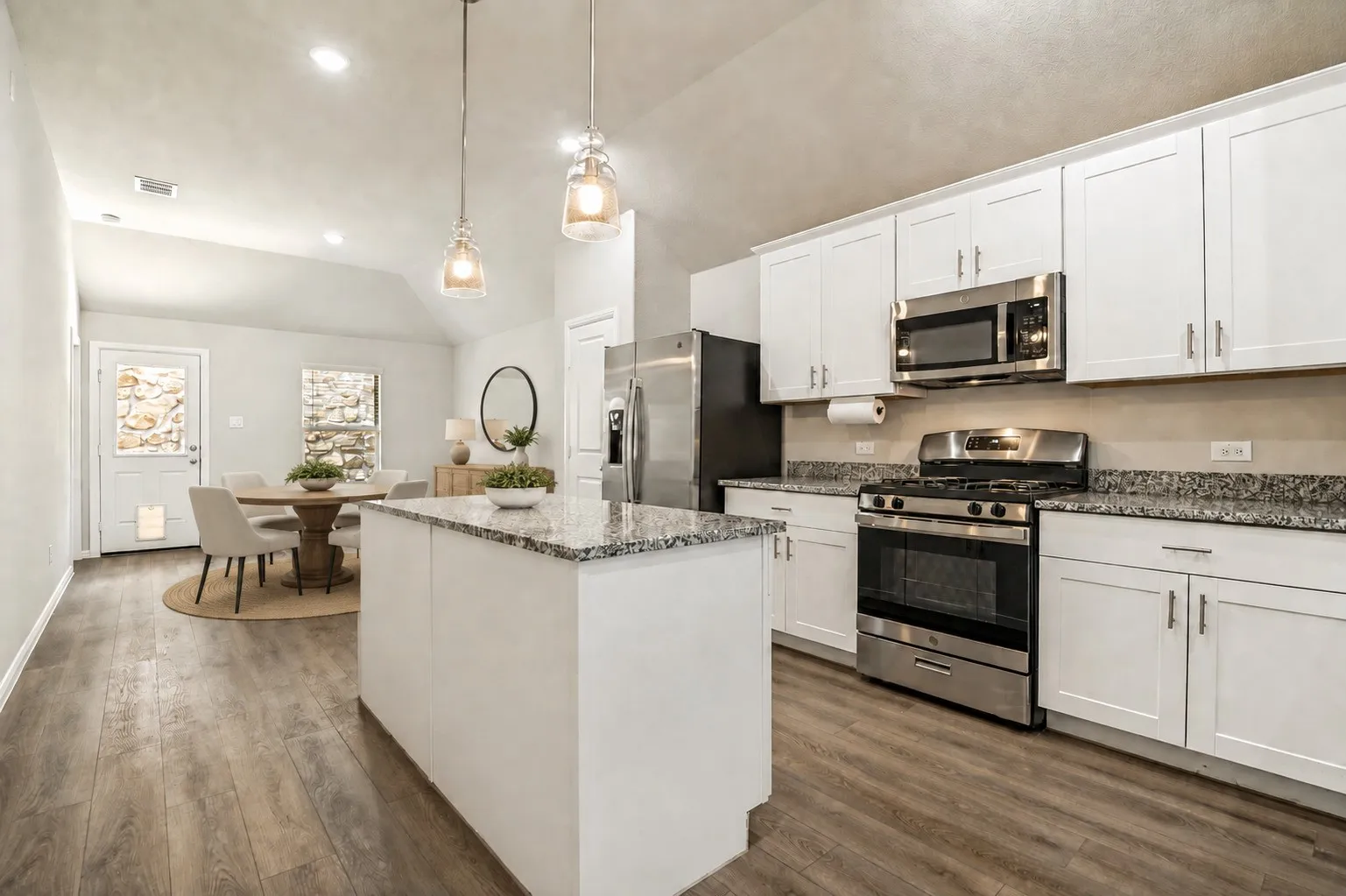 Kitchen featuring white shaker cabinetry, stainless steel appliances, granite countertops, and wood-finish flooring (virtually staged)