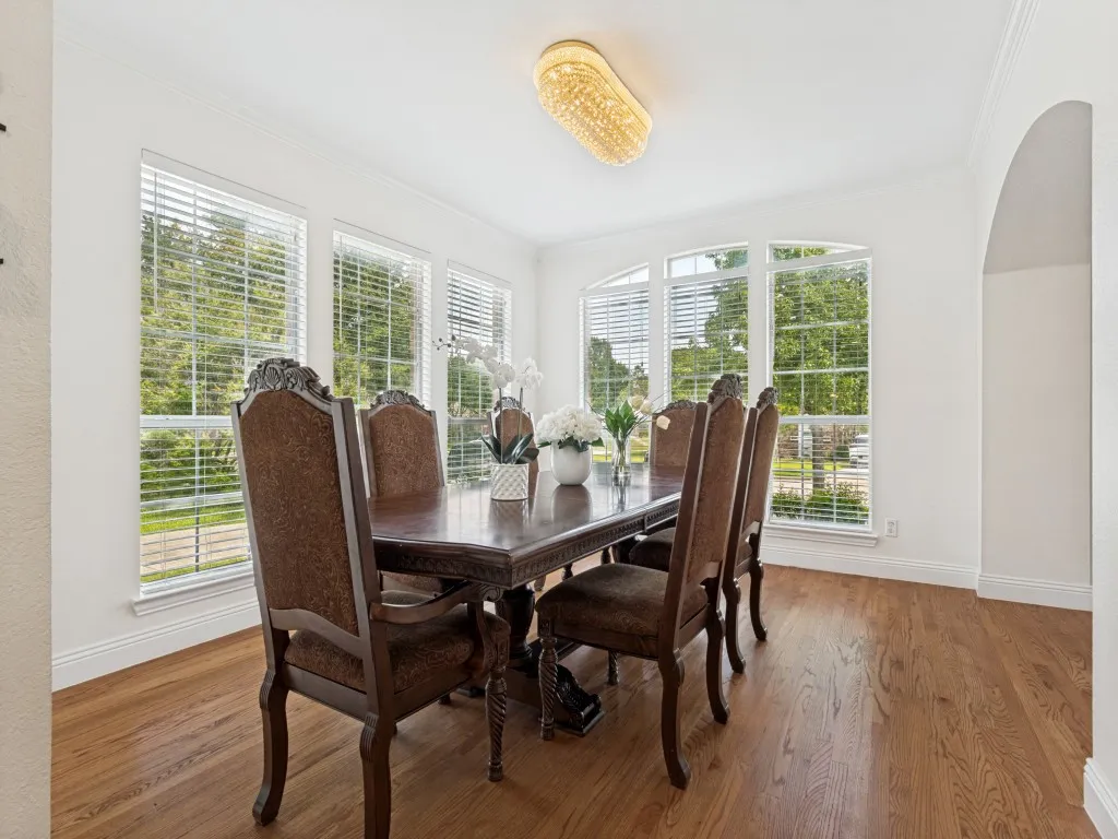 Dining area featuring wood-finish flooring, white baseboards, and crown molding