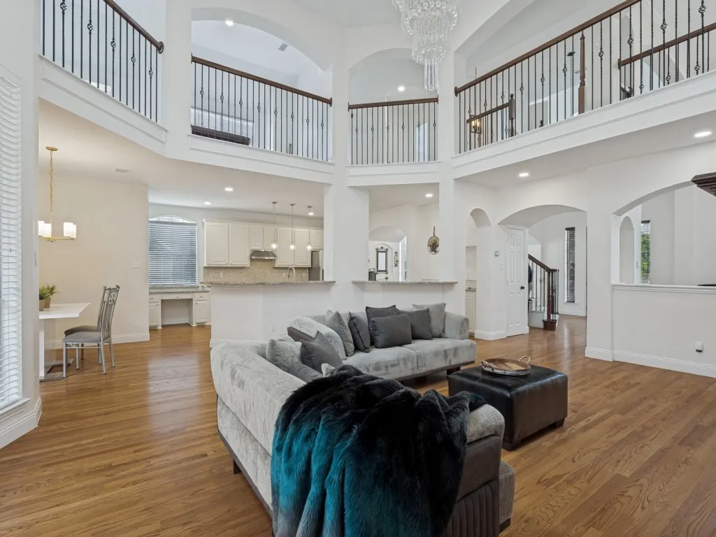 Two-story living area featuring wood-finish flooring and a tiered chandelier