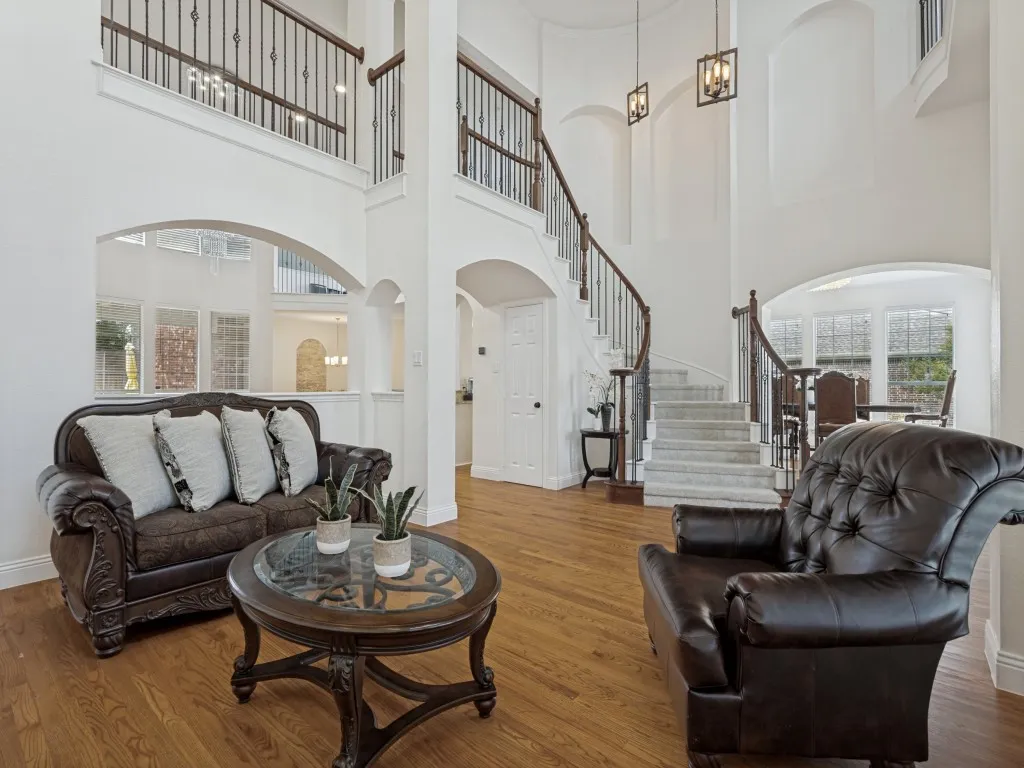 Two-story entryway featuring a grand curved staircase with wrought iron balusters and wood handrails, wood-finish flooring, and recessed arch wall​​‌​​​​‌​​‌‌​‌‌​​​‌‌​‌​‌​‌​​​‌​​ details