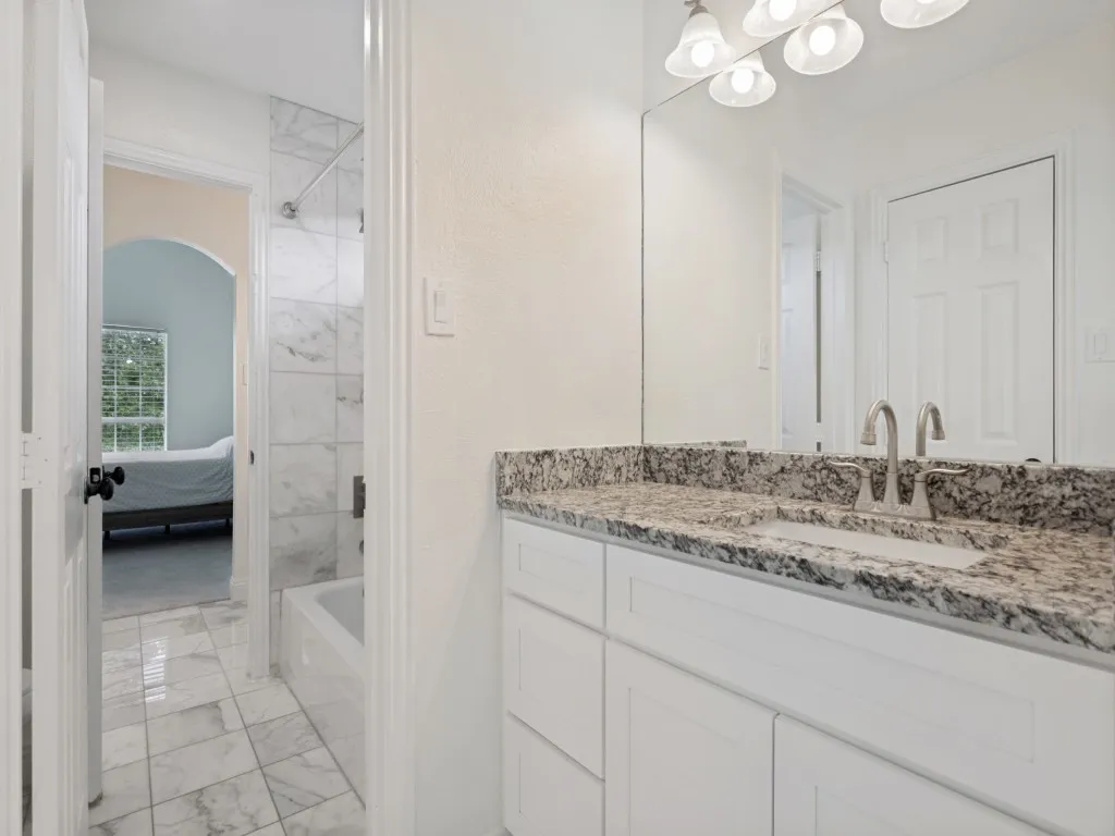 Bathroom vanity featuring a speckled countertop, undermount sink, and brushed nickel faucet