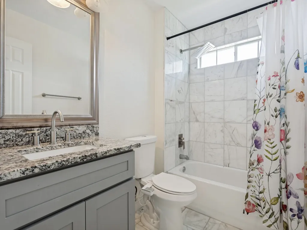 Bathroom featuring a gray vanity with granite countertop, undermount sink, and brushed nickel faucet