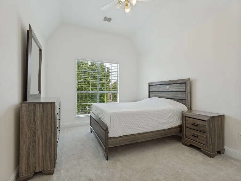 Carpeted room featuring a vaulted ceiling with ceiling fan and a window with blinds