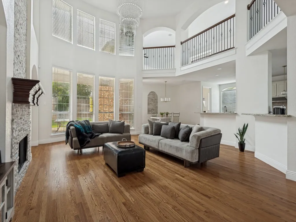 Two-story living area featuring wood-finish flooring and a fireplace with stone surround