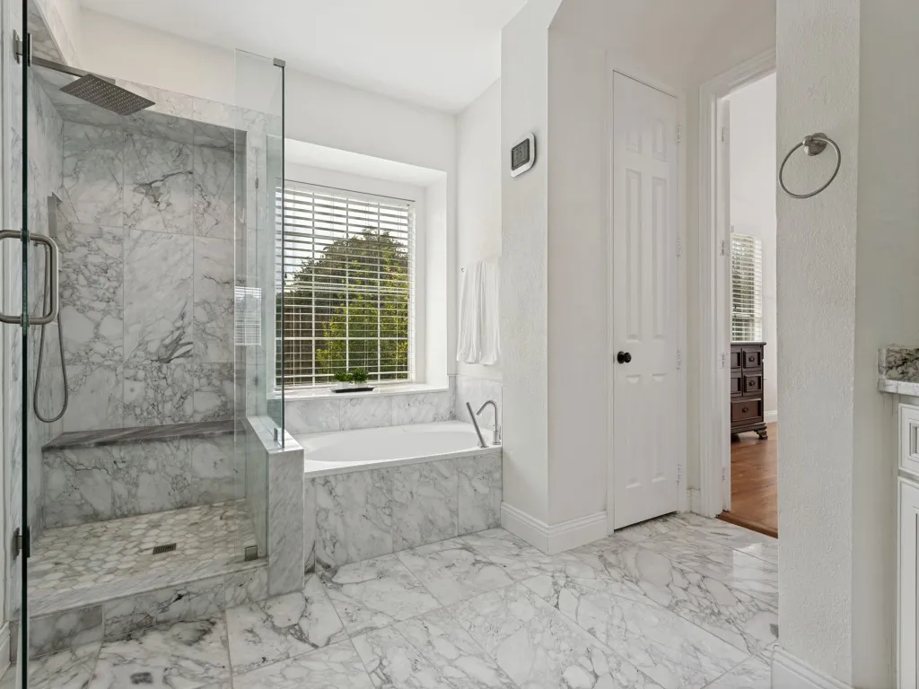 Spacious bathroom featuring a glass-enclosed shower with a built-in bench, a rain showerhead, and intricate tilework