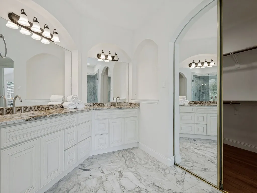 Bathroom featuring dual vanity areas with white cabinetry and stone countertops