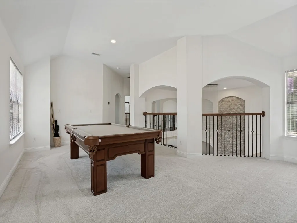 Expansive loft space featuring vaulted ceilings and light-colored carpeting
