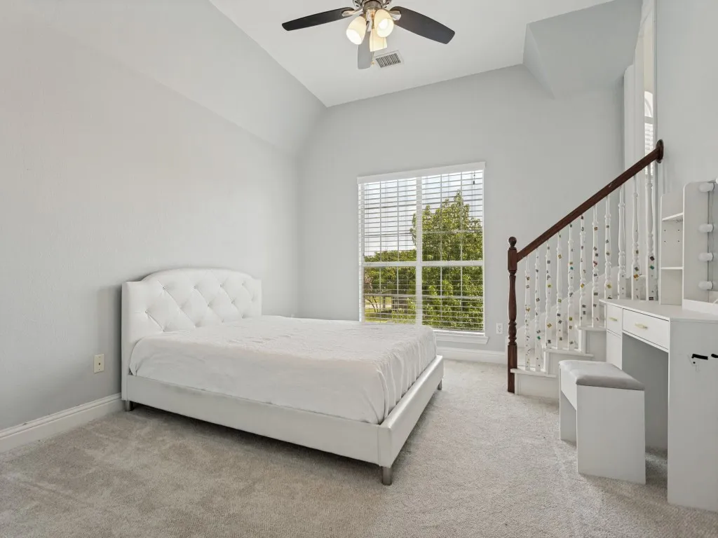 Spacious room featuring vaulted ceilings, a large window with white blinds, and light gray carpet flooring