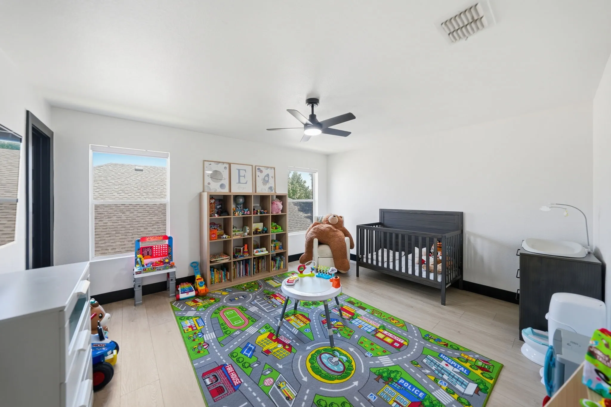 Bright room featuring light wood-finish flooring, white walls, and multiple windows providing natural light