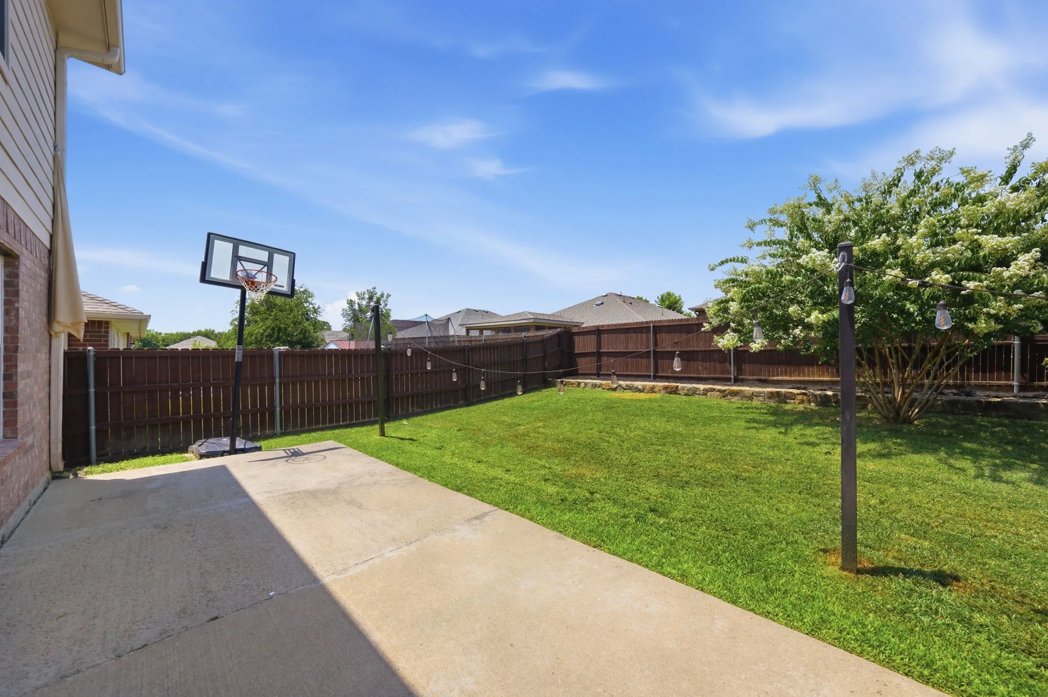 Expansive backyard featuring a large concrete patio, manicured lawn, and a privacy​​‌​​​​‌​​‌‌​‌‌​​​‌‌​‌​‌​‌​​​‌​​ fence