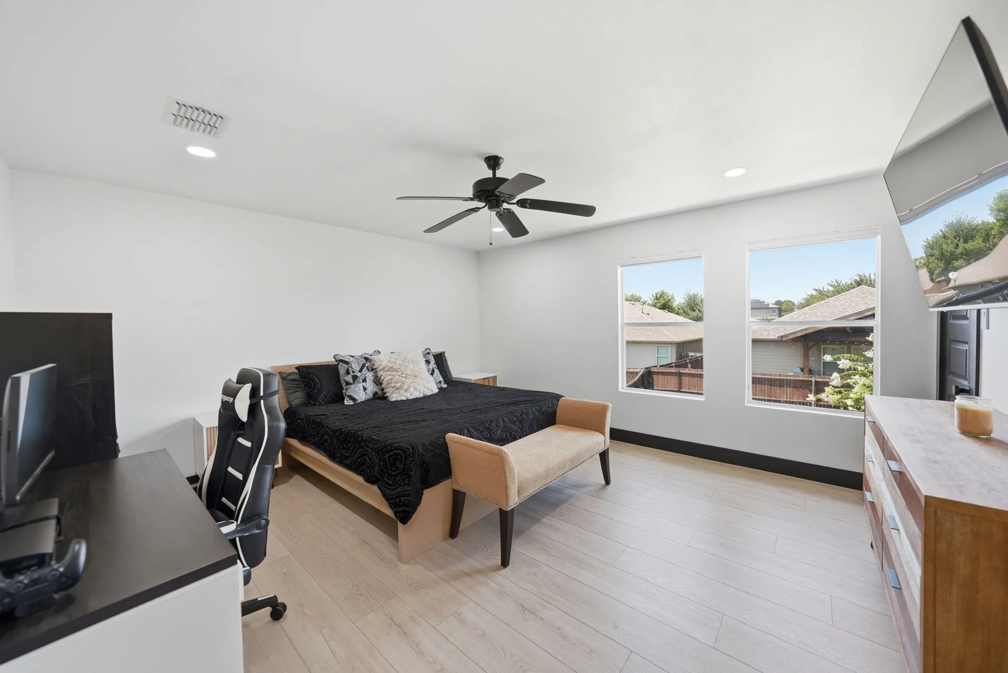 Spacious room featuring light wood-finish flooring and two large windows