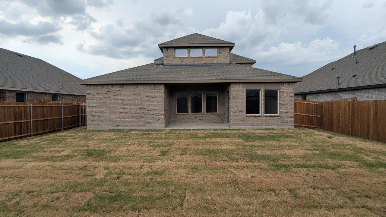 Rear exterior featuring light-colored brick facade and a multi-level roofline with dormer windows