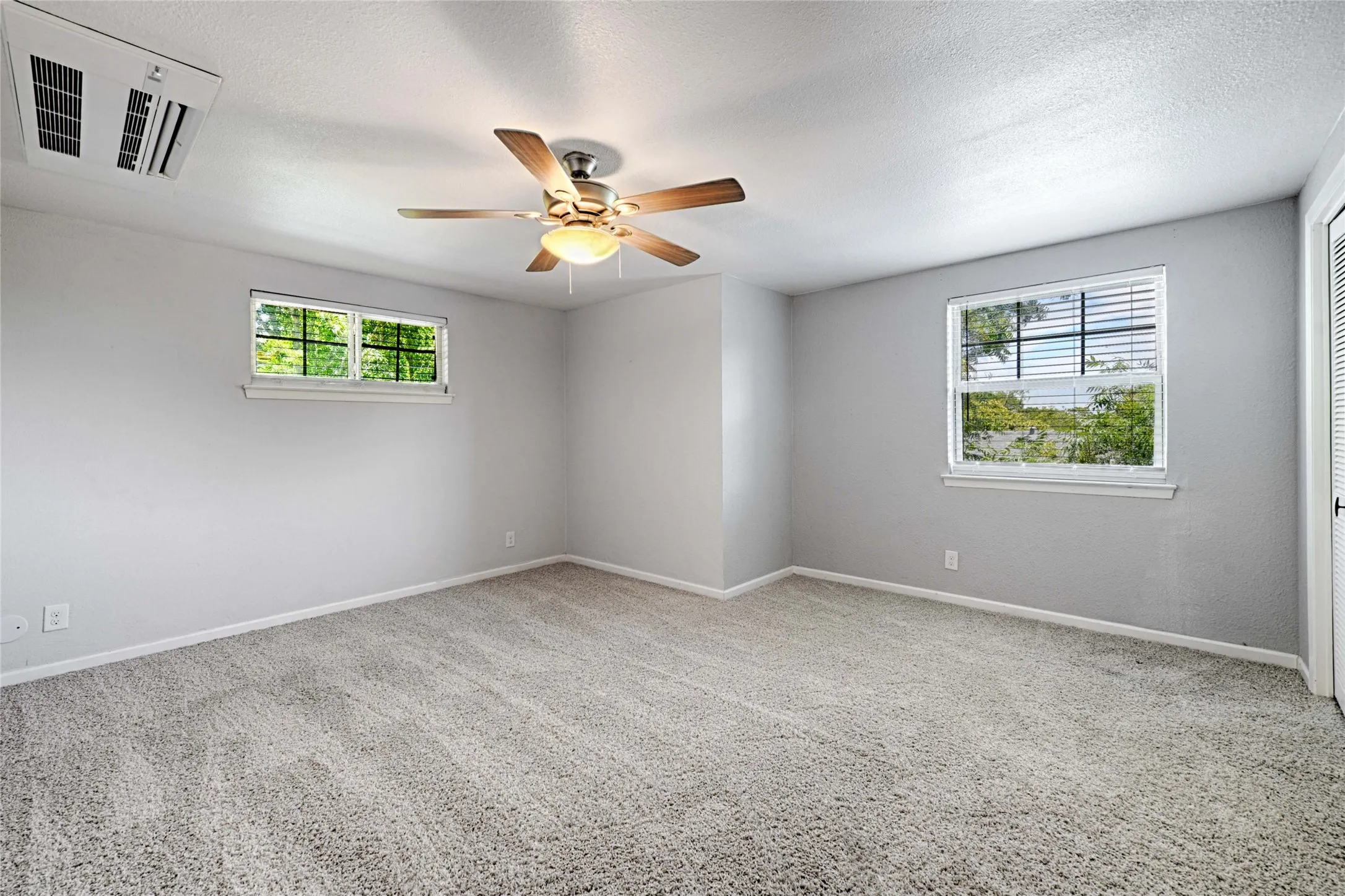 Spacious interior room with light gray walls and plush gray carpeting