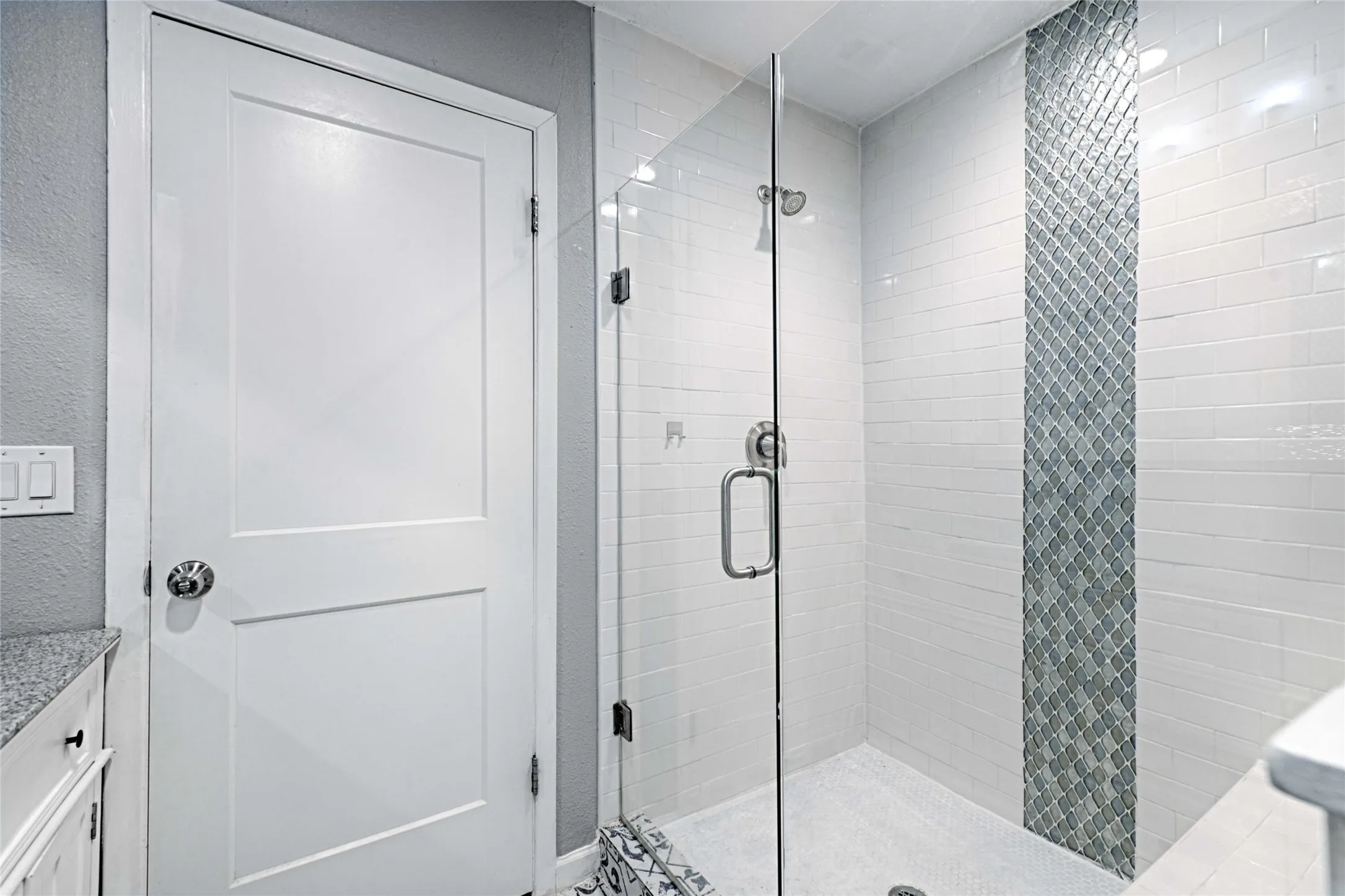 Walk-in shower with clear glass enclosure and subway tile surround